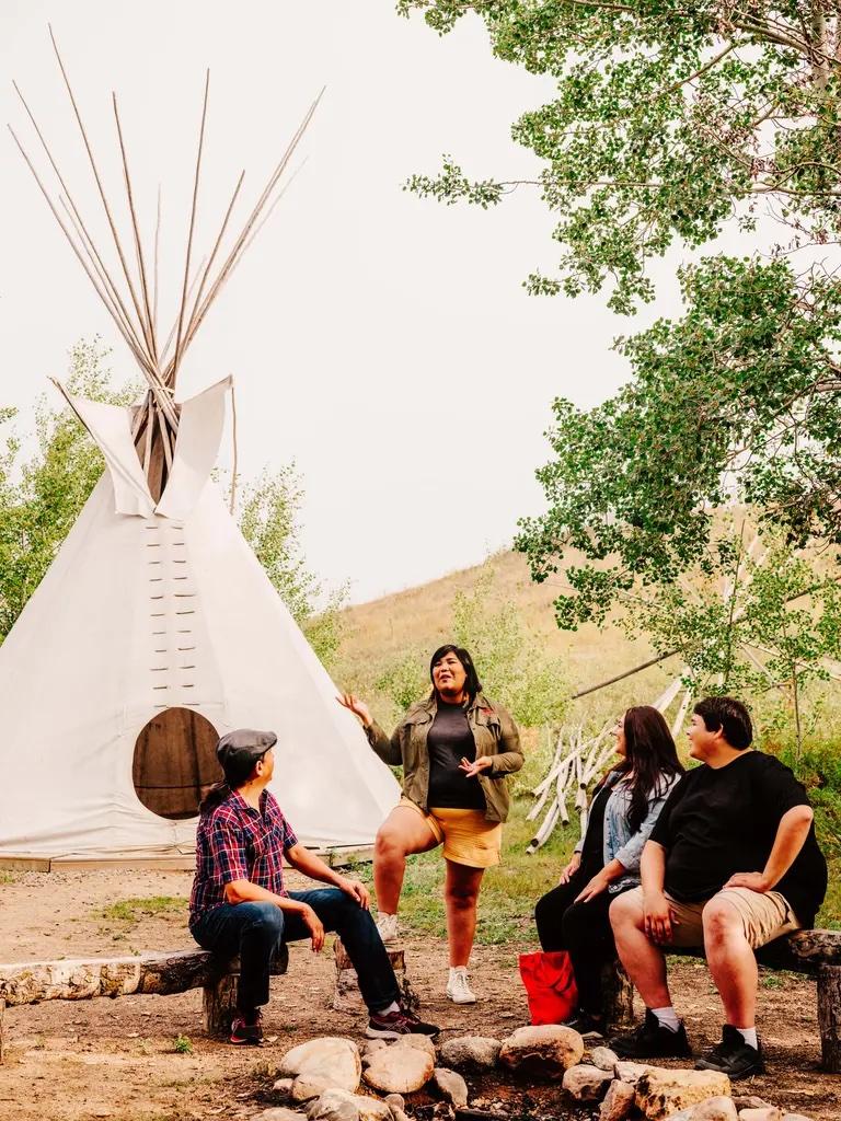 A person leading an Indigenous cultural tour next to a teepee