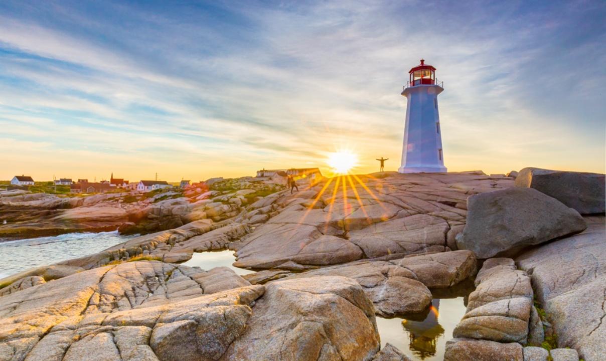 Lighthouse on rocks with the sun appearing from behind