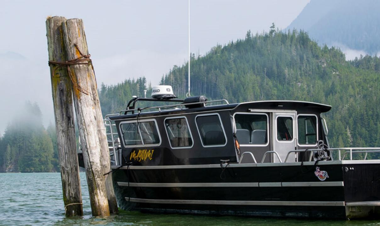 A fishing boat moored in front of forested hills.