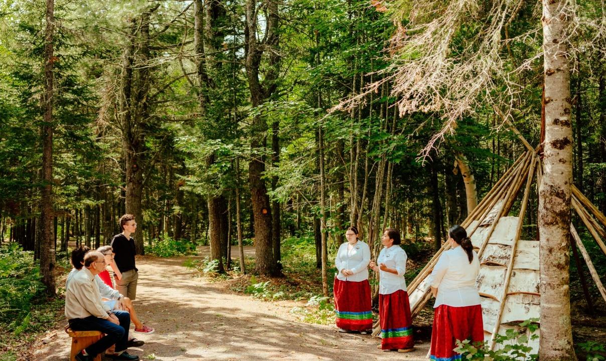 Indigenous tour guides speak in front of a group in the forest