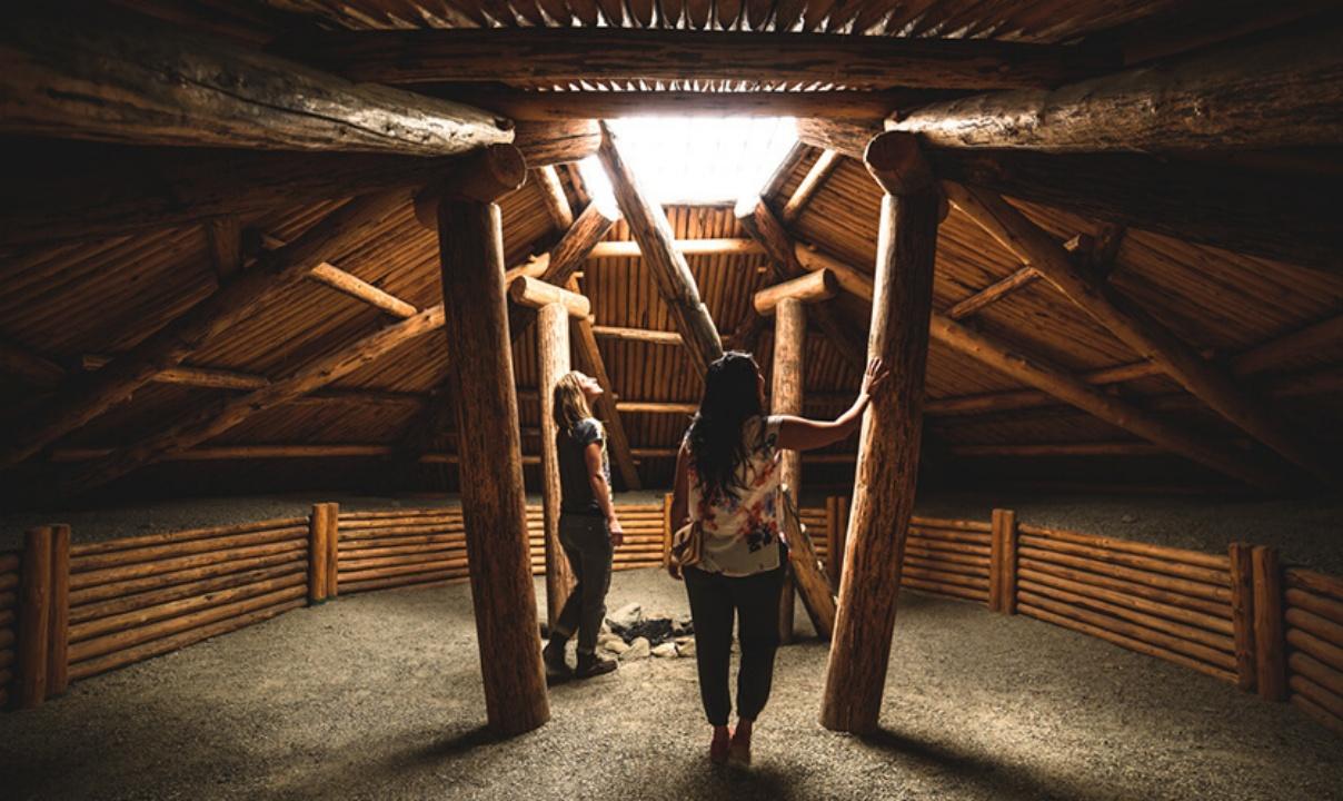 Two people standing inside a wooden structure at the NK'MIP Desert Cultural Centre