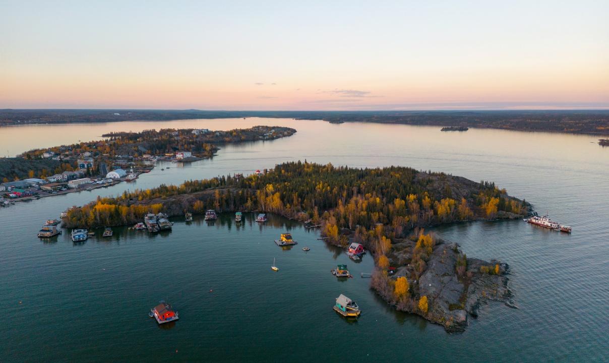 Small wooded, rocky islands with scattered buildings and house boats off the shore.