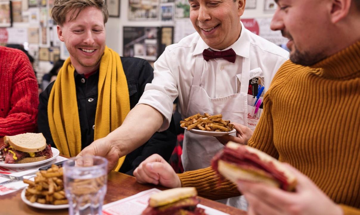 Two men being served poutine at a restaurant.