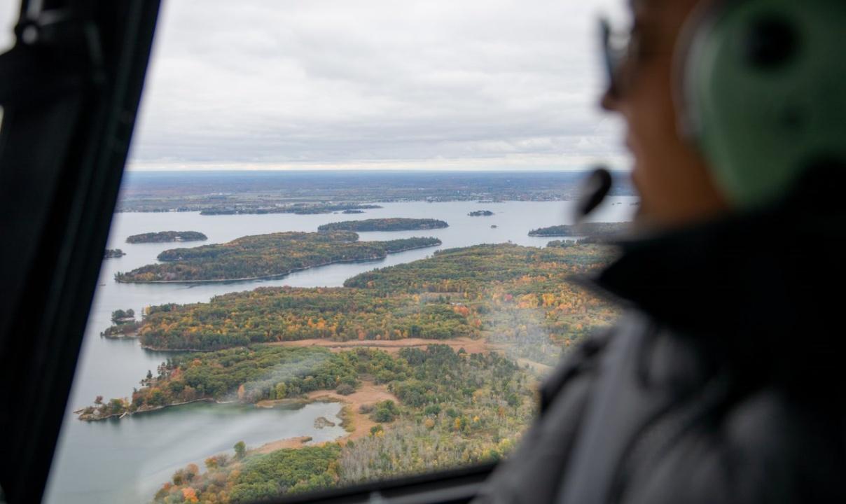 A person looking out the window of a helicopter flying over Thousand Islands, Ontario.