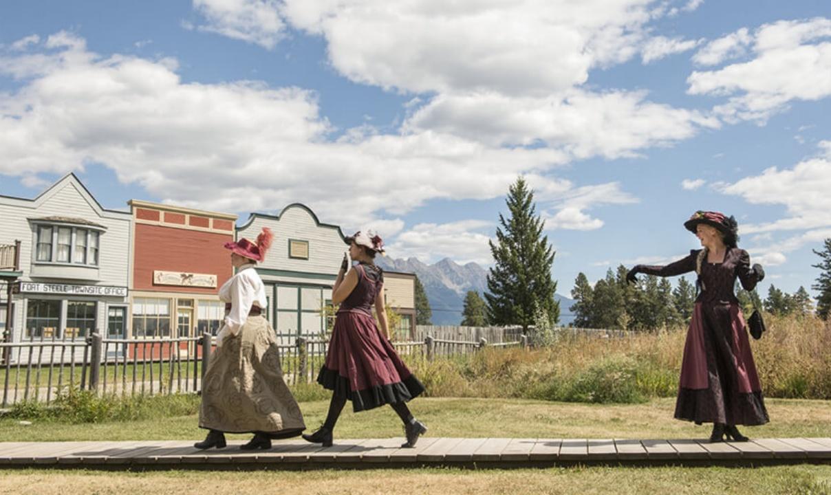 Three women dressed in period clothing walking through Fort Steele Heritage Town.