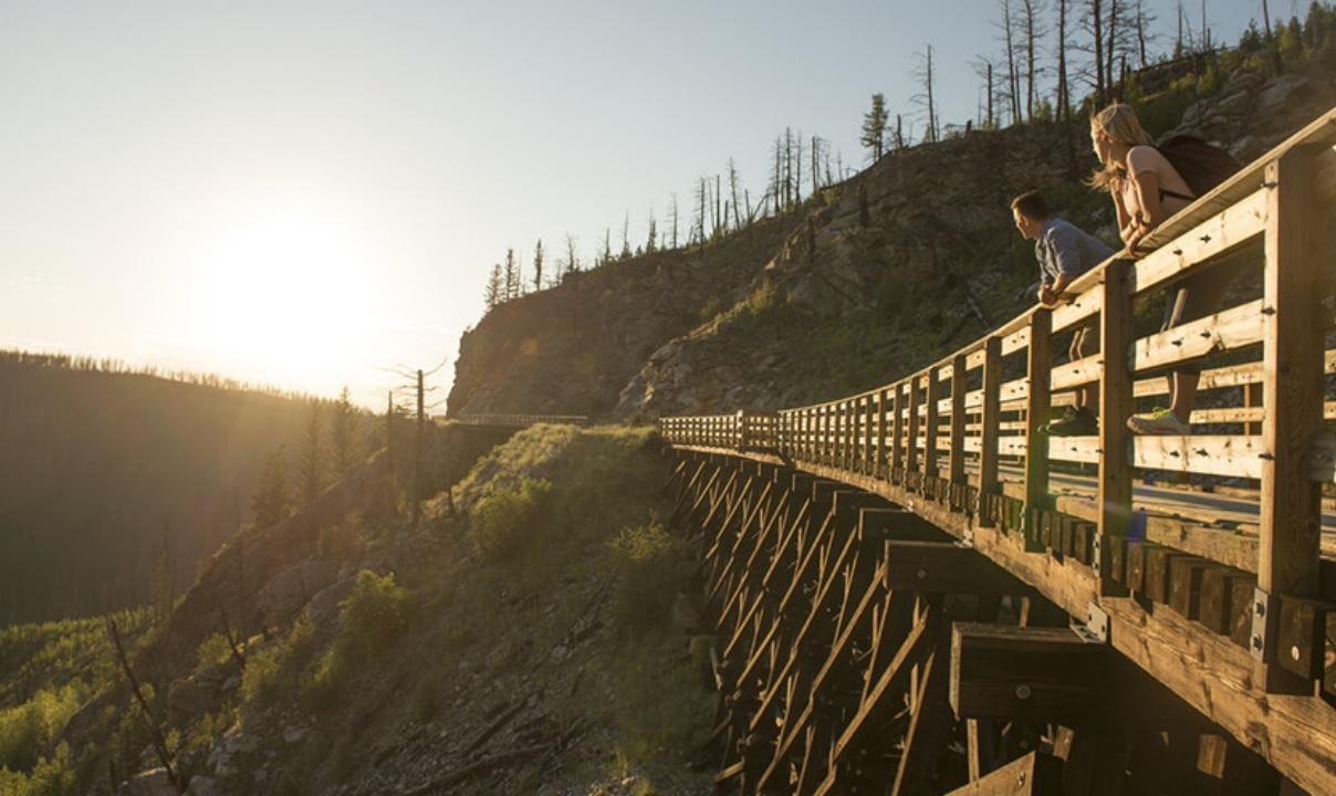 Two people standing on a bridge overlooking Myra Canyon.