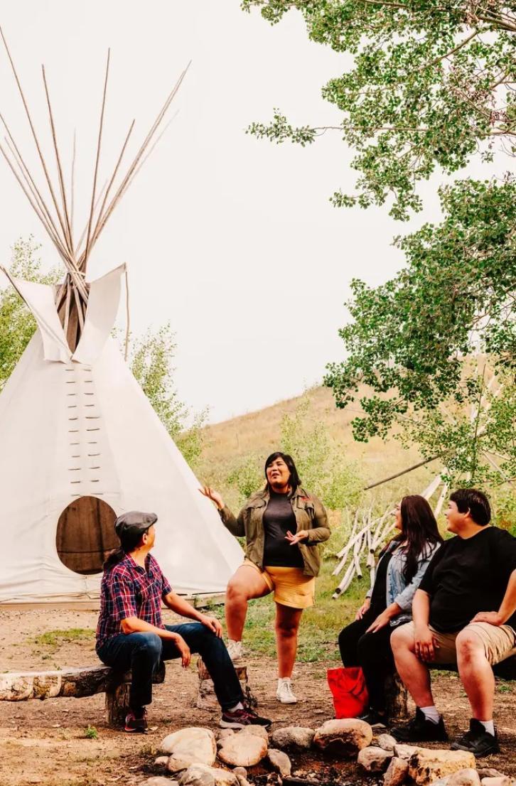 A person leading an Indigenous cultural tour next to a teepee