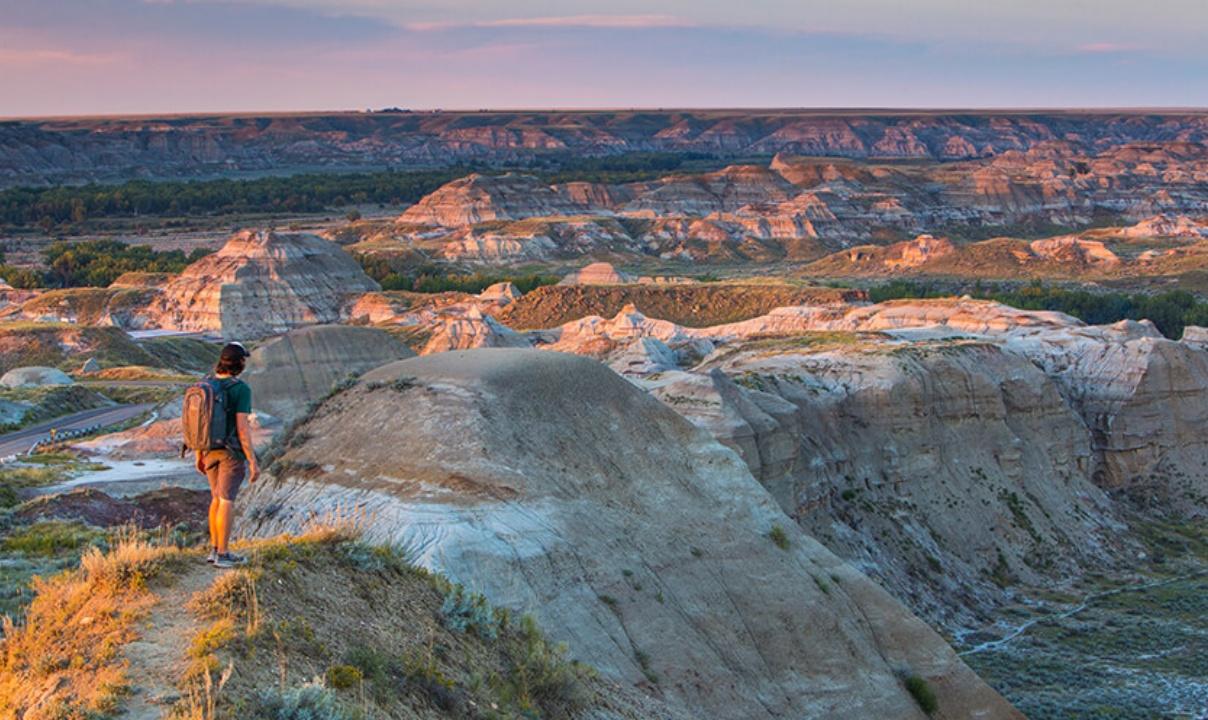 A person hiking through the Badlands at sunset.