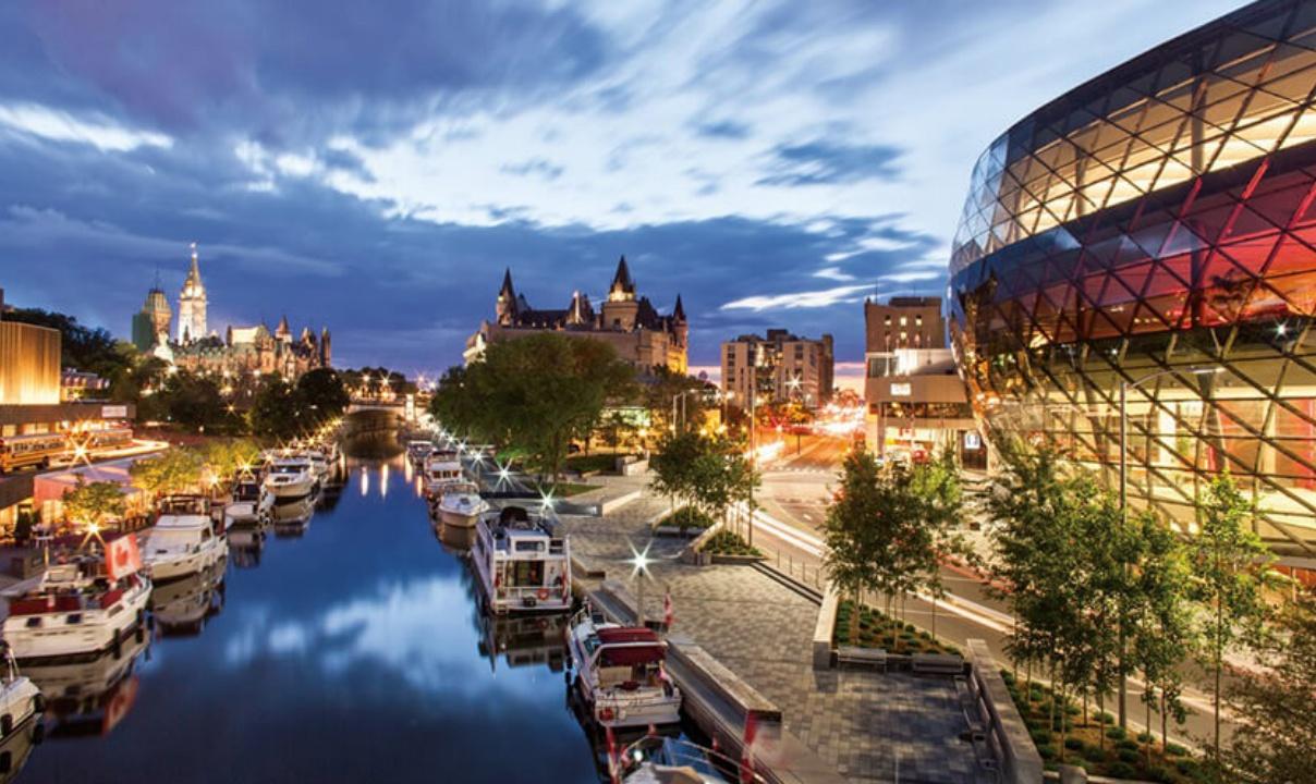 Boats along the Rideau Canal in front of the Rogers Centre at twilight in Ottawa.