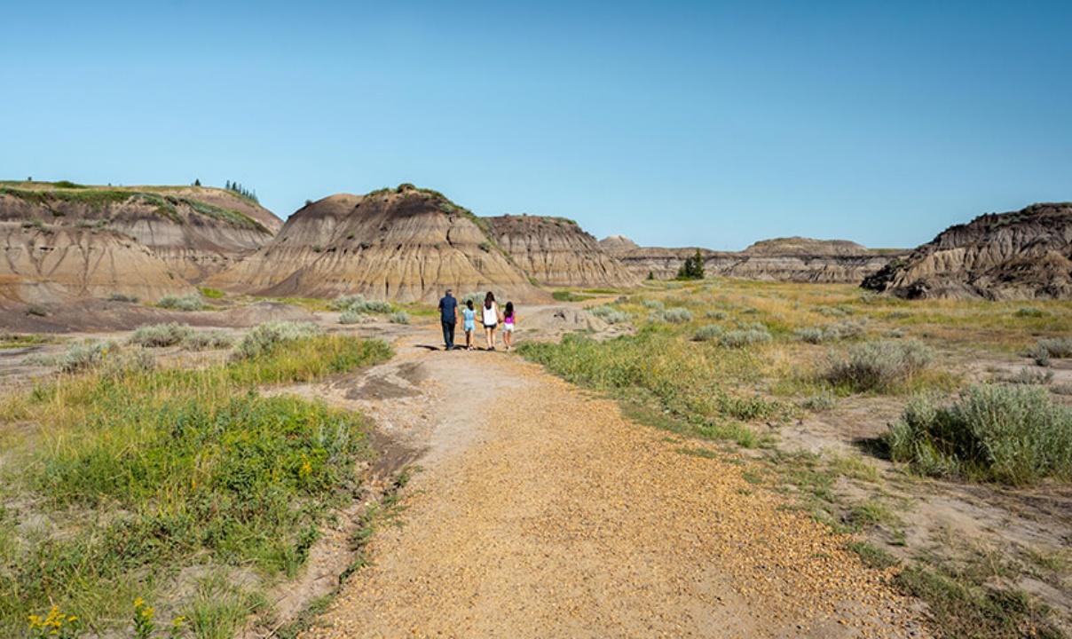 A family walking on a path through the Canadian Badlands.