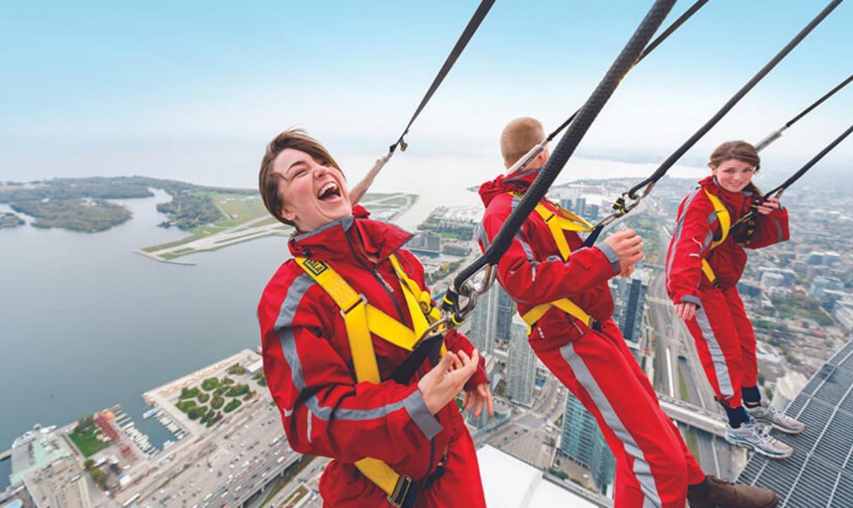Three people tethered in and leaning back from the edge on the CN Tower EdgeWalk
