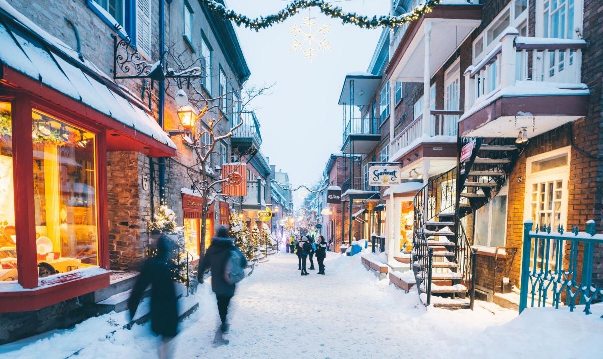 People walking down a snowy, shop-lined street in Quebec City.