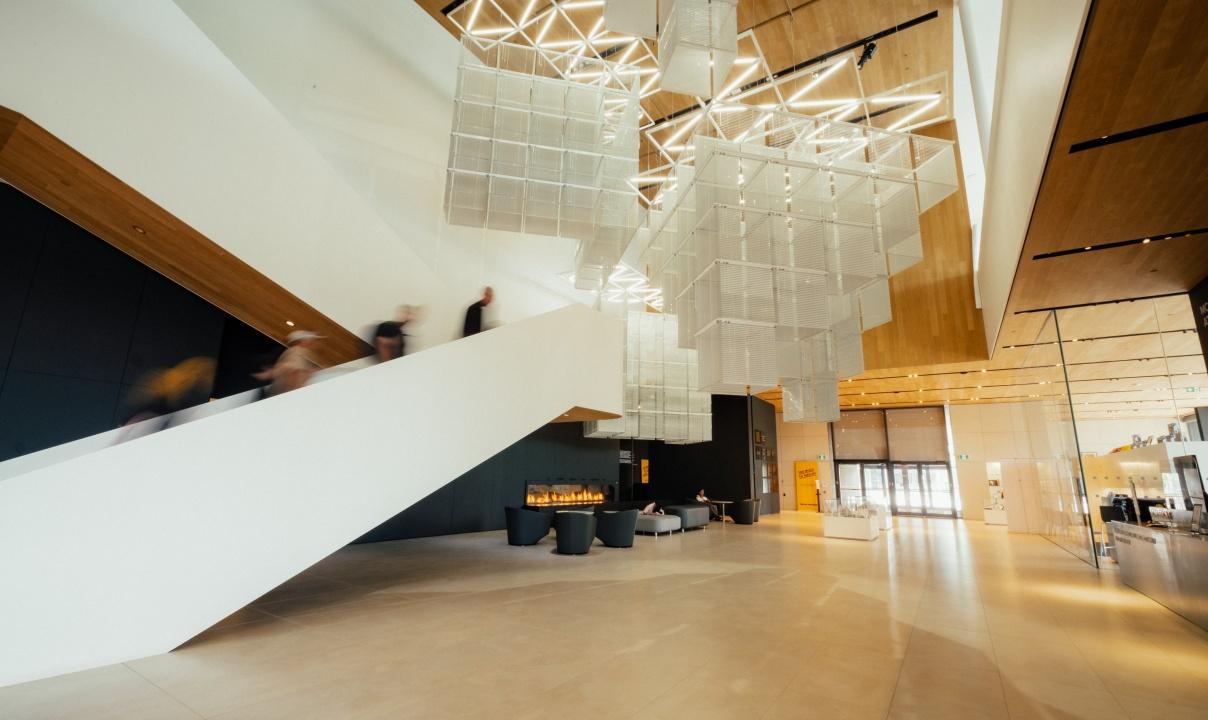 A large hanging sculpture next to a white staircase in an entrance hall of the Remai Modern.