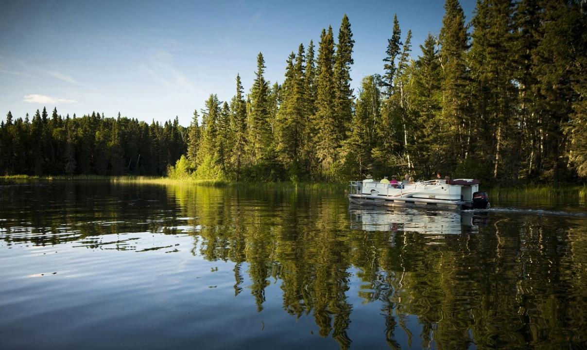 A boat anchored on a tree-lined lake.
